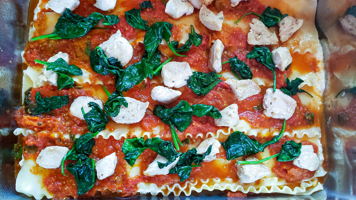 Sauce spread on the noodles topped with spinach and mozzarella.