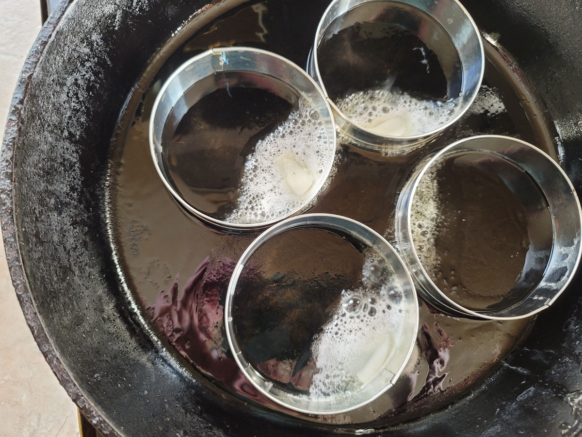 Melted butter in English muffin rings in a cast iron skillet.