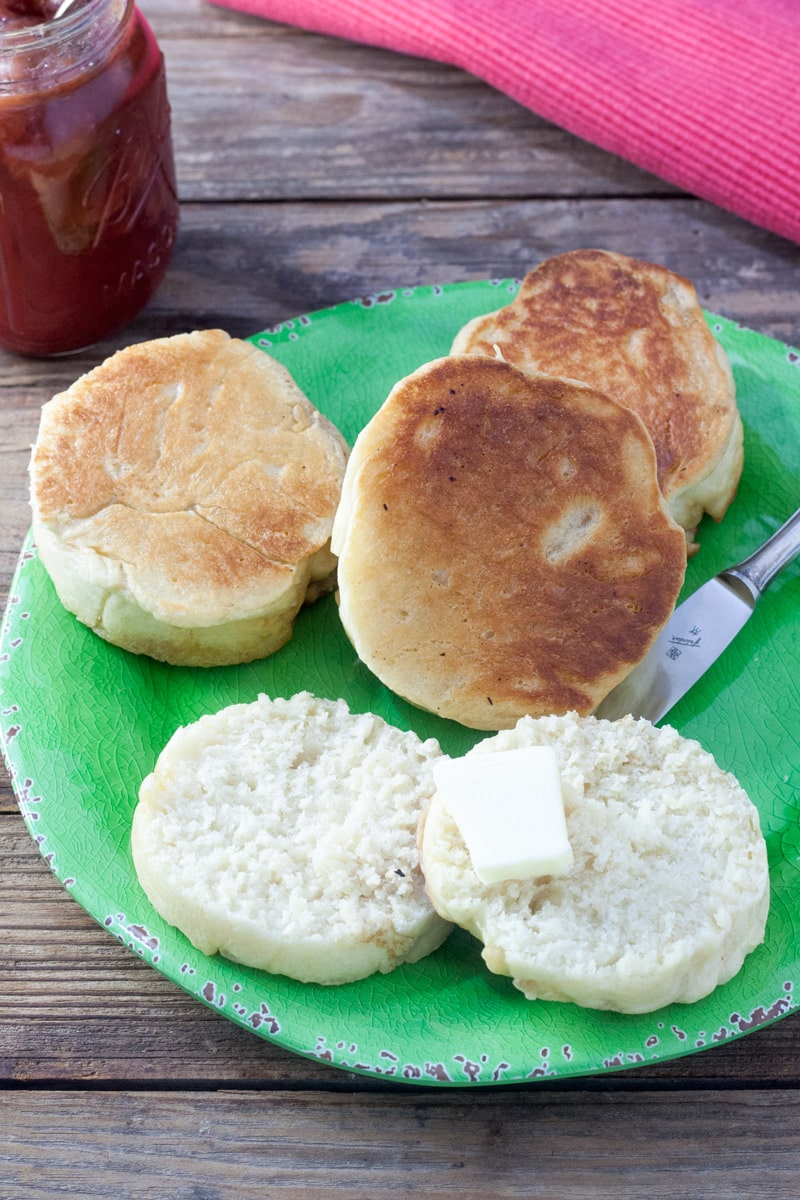 Cut English muffin, untoasted with pat of butter on green plate