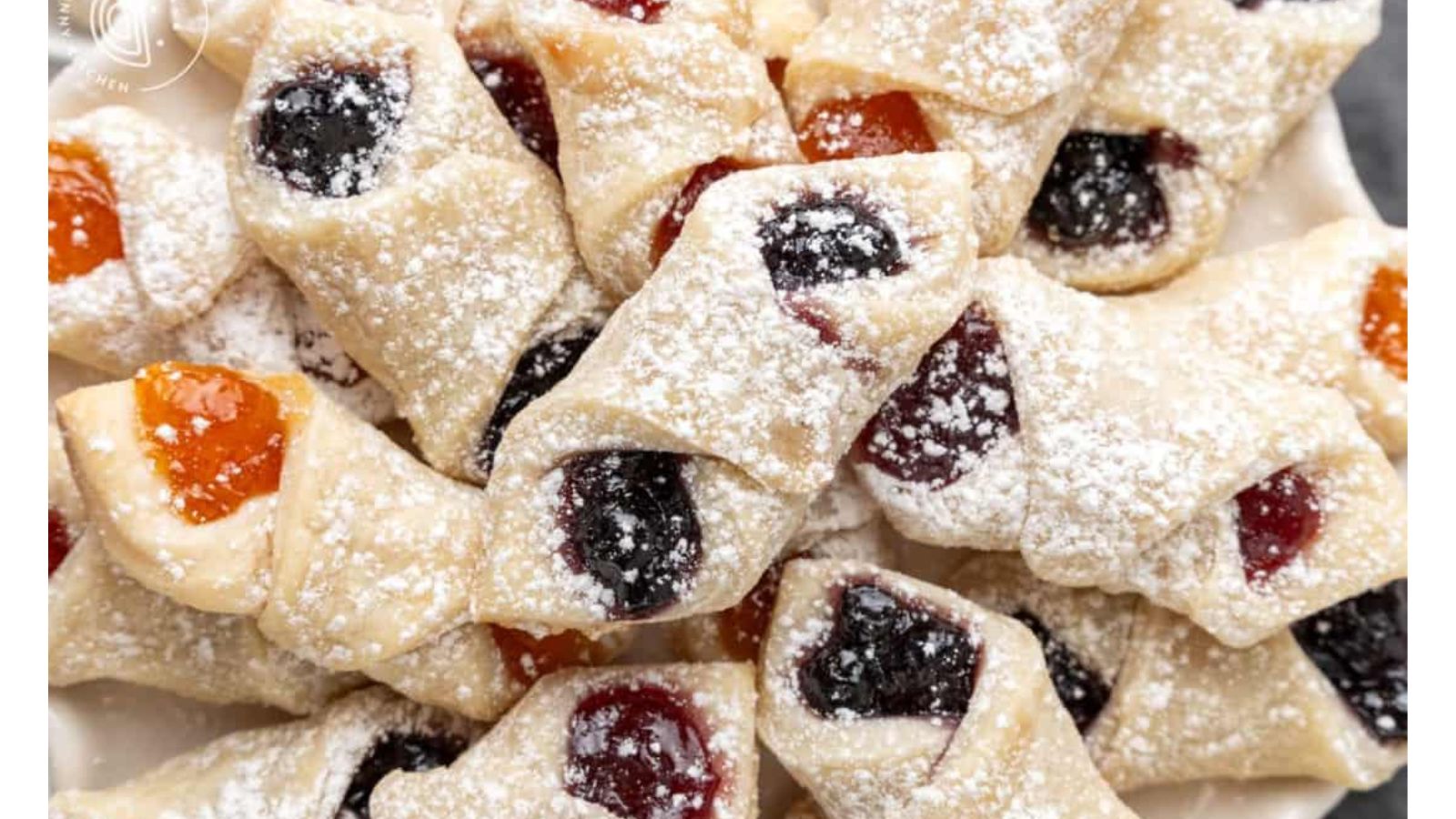 Powdered sugar covered cookies with different colored jam.