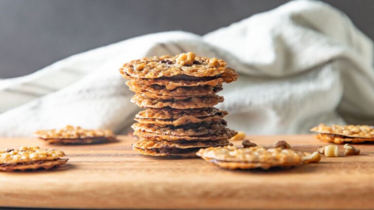 Stacked lace cookies on a wooden board.