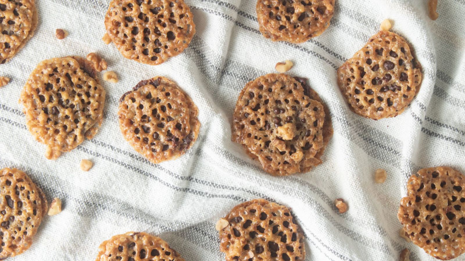 Overhead view of lace cookies on a white kitchen towel.