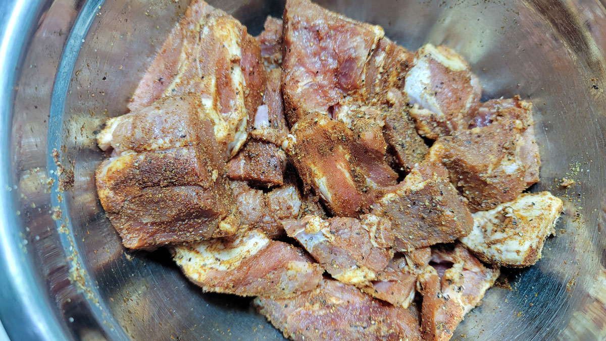 Seasoned meat in a metal bowl.