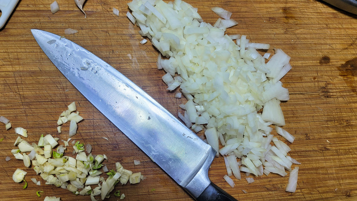 Chopped onions and garlic on a board.