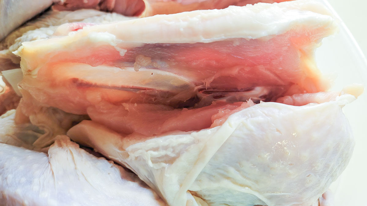 Knife cutting down along the breast bone to remove the breast meat.