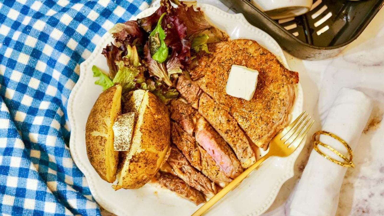 Steak with side salad and butter on a plate.