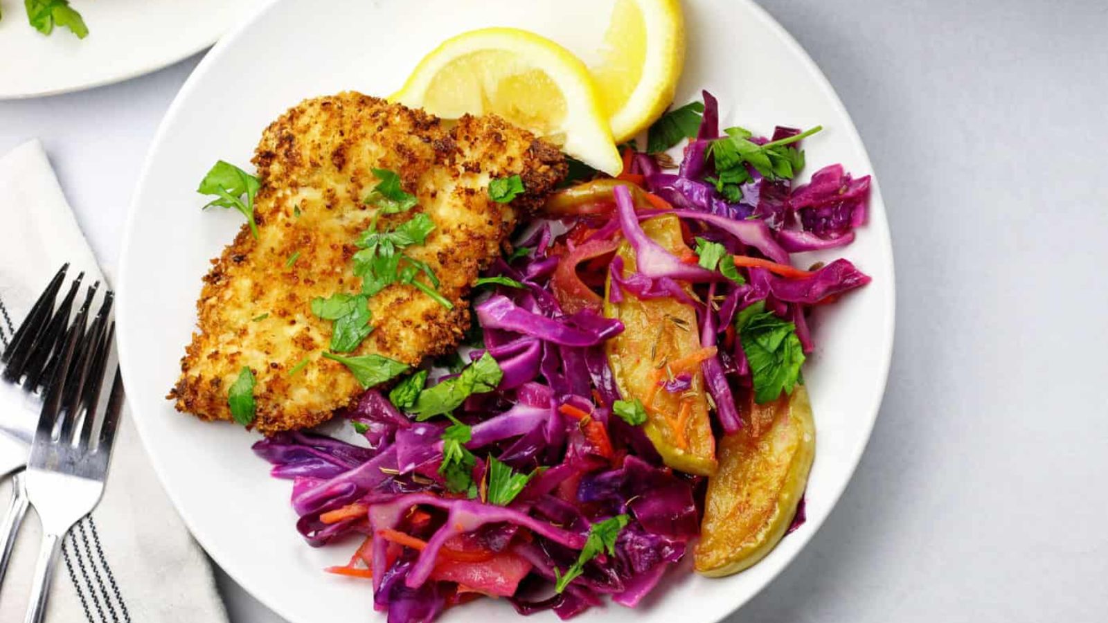 Schnitzel with cabbage and sliced lemons.