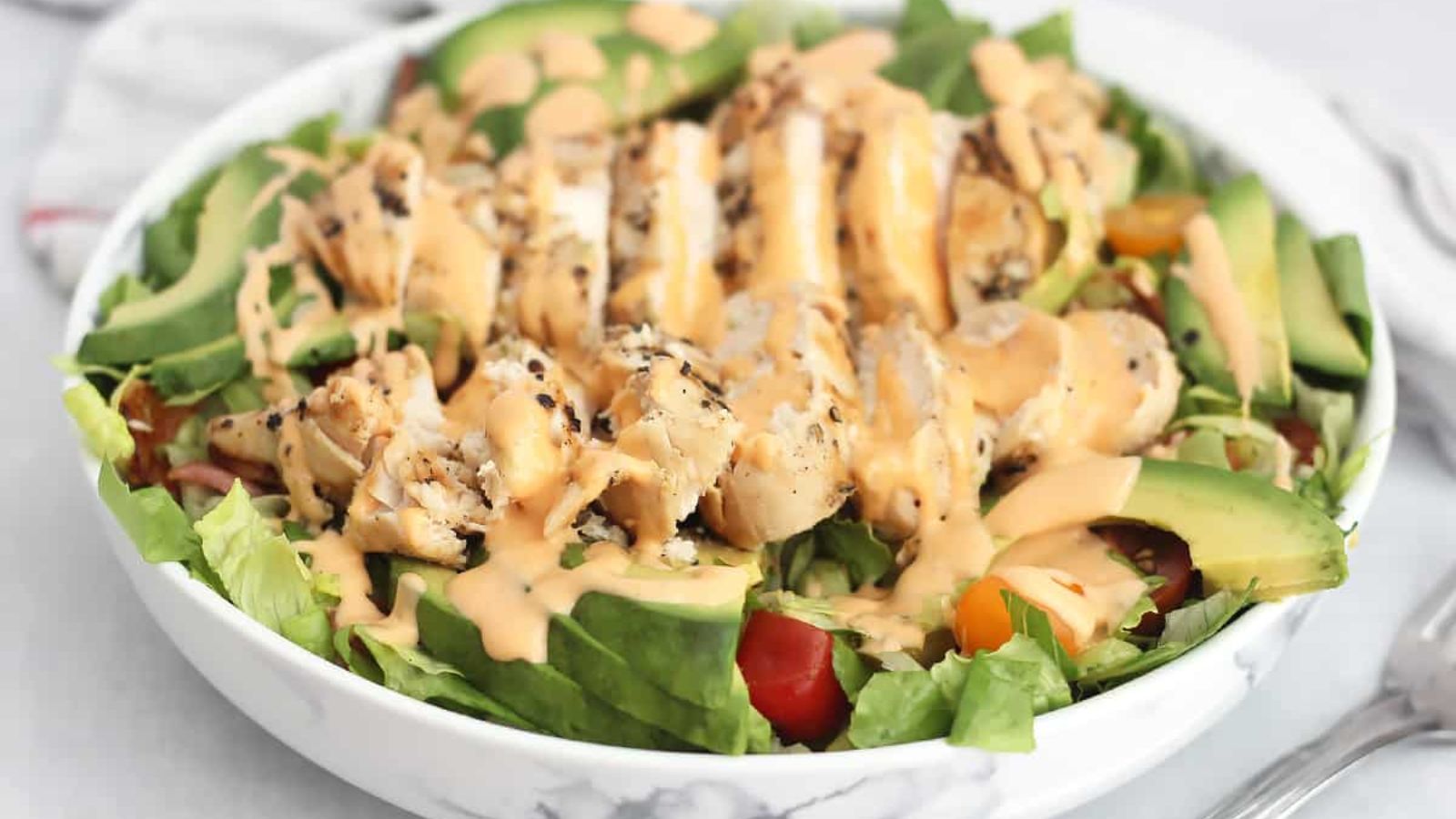 Chicken avocado salad with dressing.