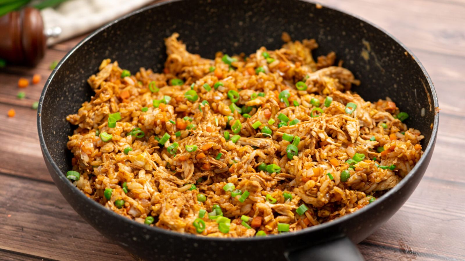 Chicken fried rice on a black plate.