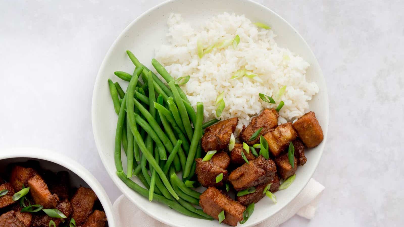 Pork with green beans and rice on a plate.