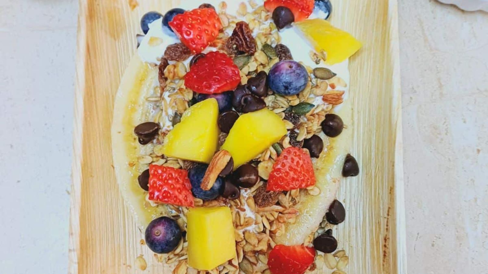 Banana split with yogurt, strawberries and sliced mangoes.