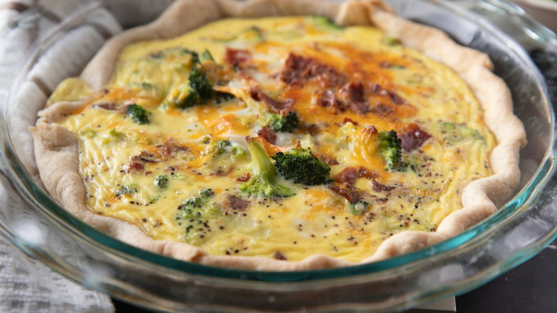 Whole quiche in a glass pie plate.