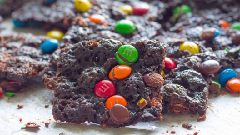 Pile of colorful M&M brittle on a white background.