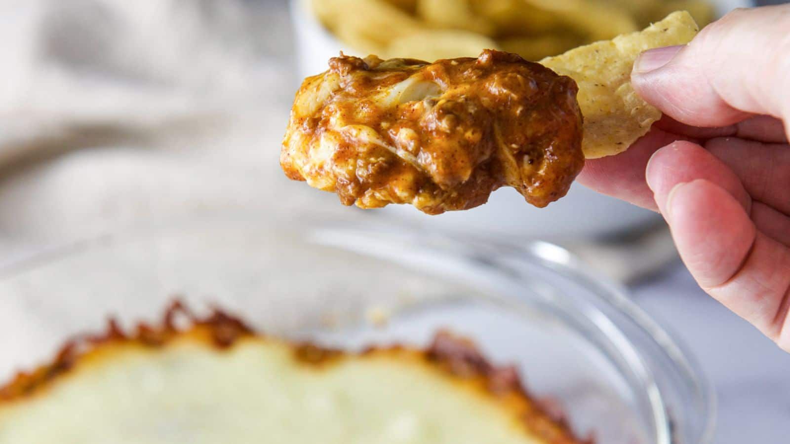 A chip dipped into chili cheese dip.