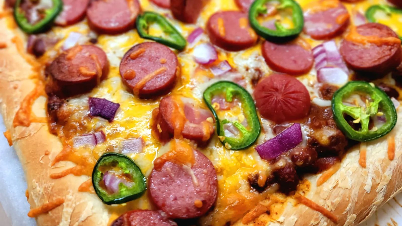 Pizza with hotdogs and jalapeno slices.