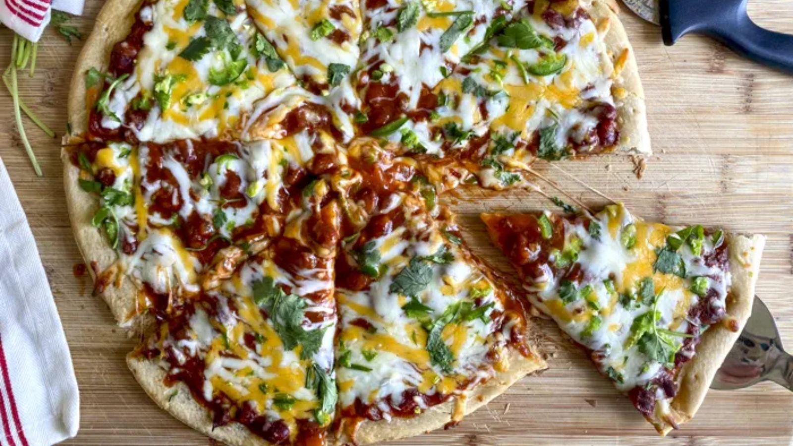 Slices of chili cheese pizza on a wooden board.