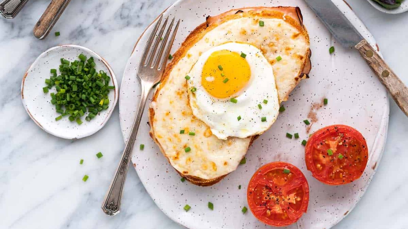 Bread with sunny side up eggs on top and sliced tomatoes on the side.