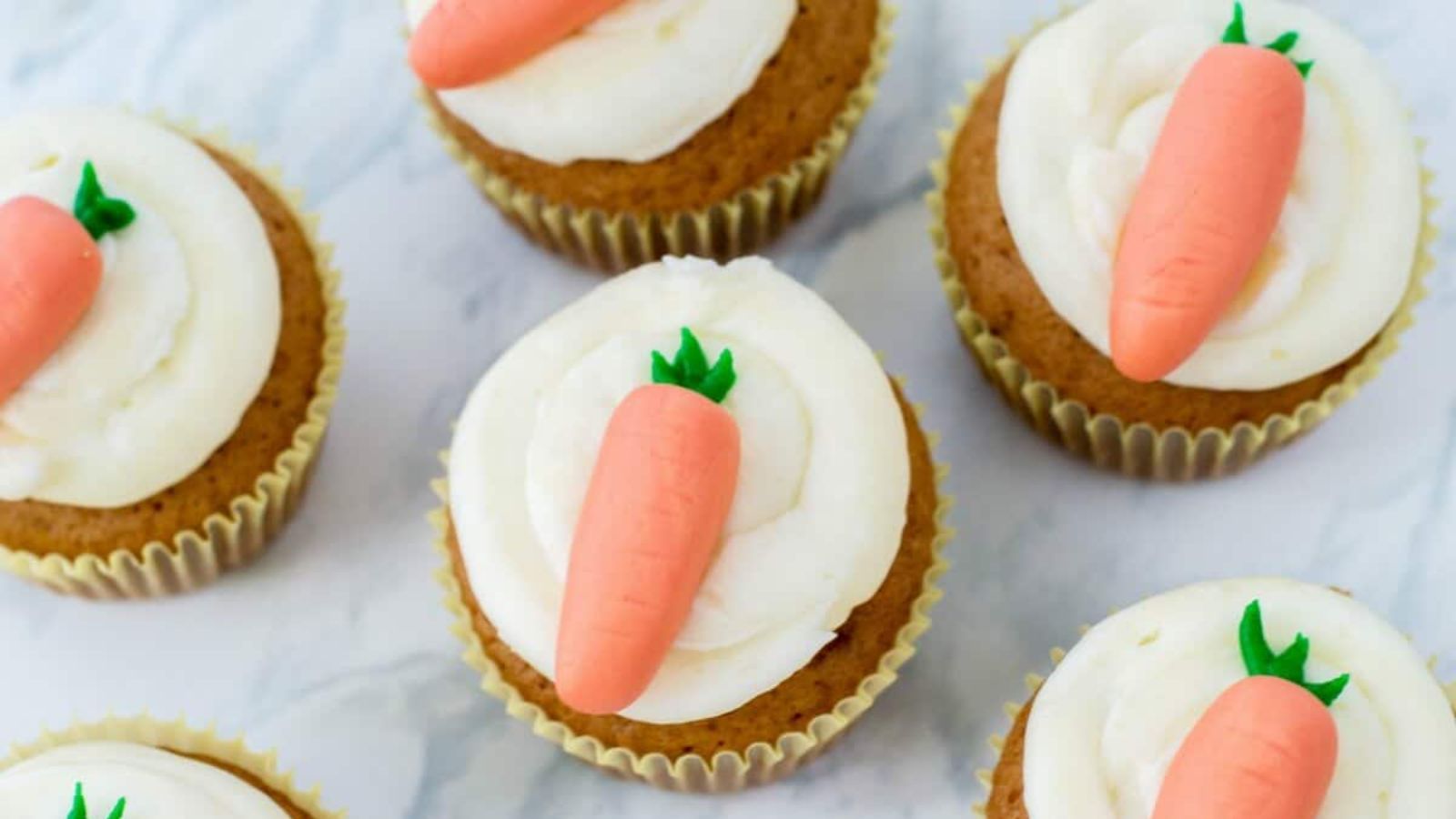 Carrot cupcakes on a marble surface.