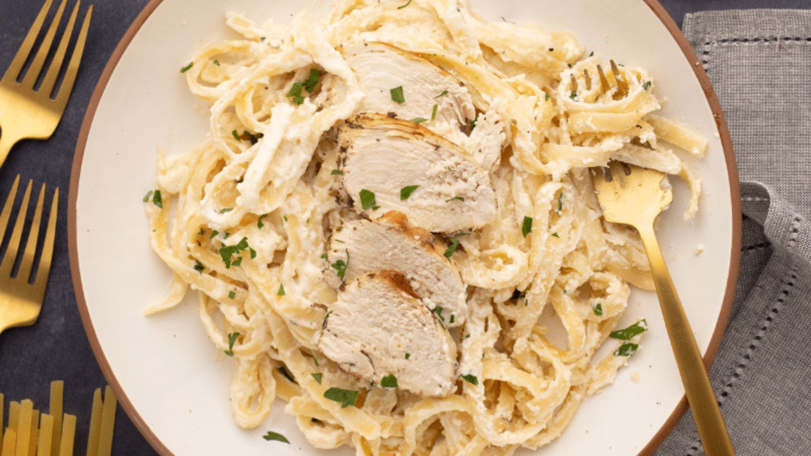 Fettuccine alfredo with sliced chicken on top.