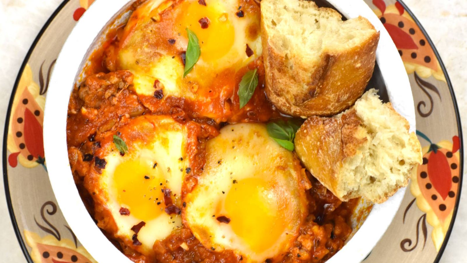 Eggs in red sauce with breads on the side.