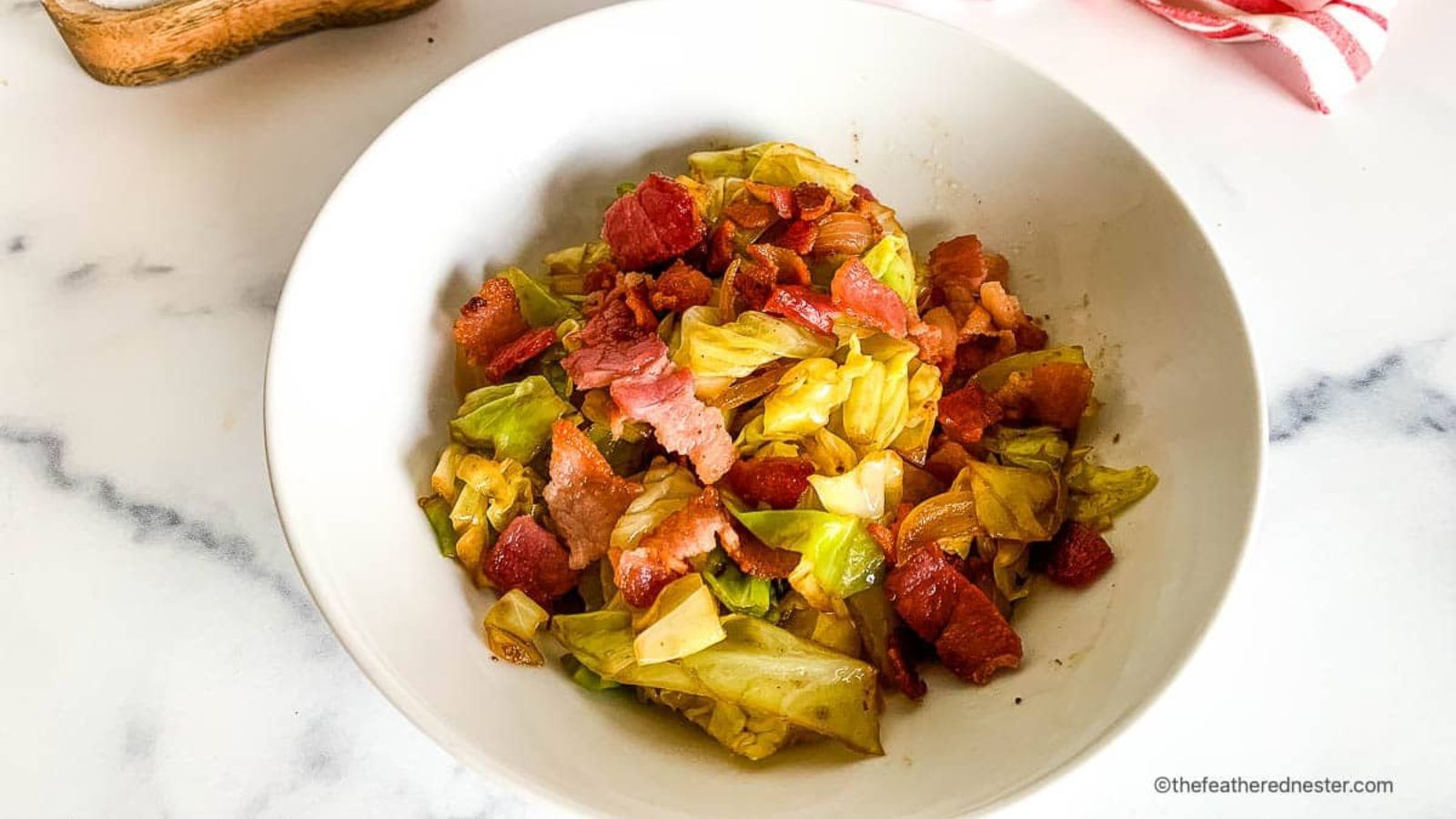 Cabbage with bacon and onions in a bowl.