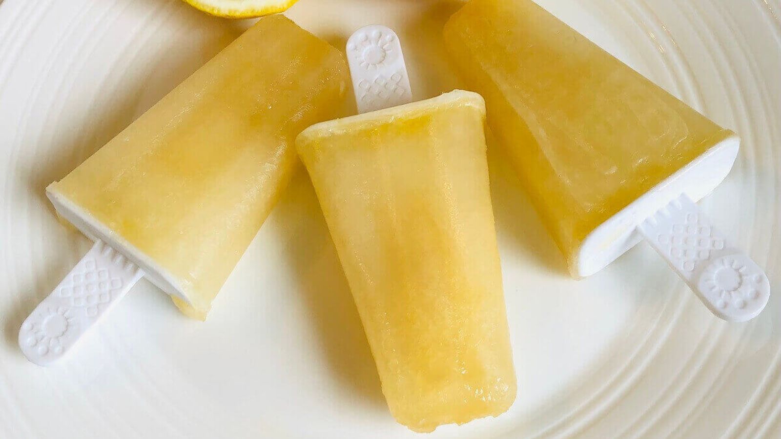 Three lemon popsicles on a plate.