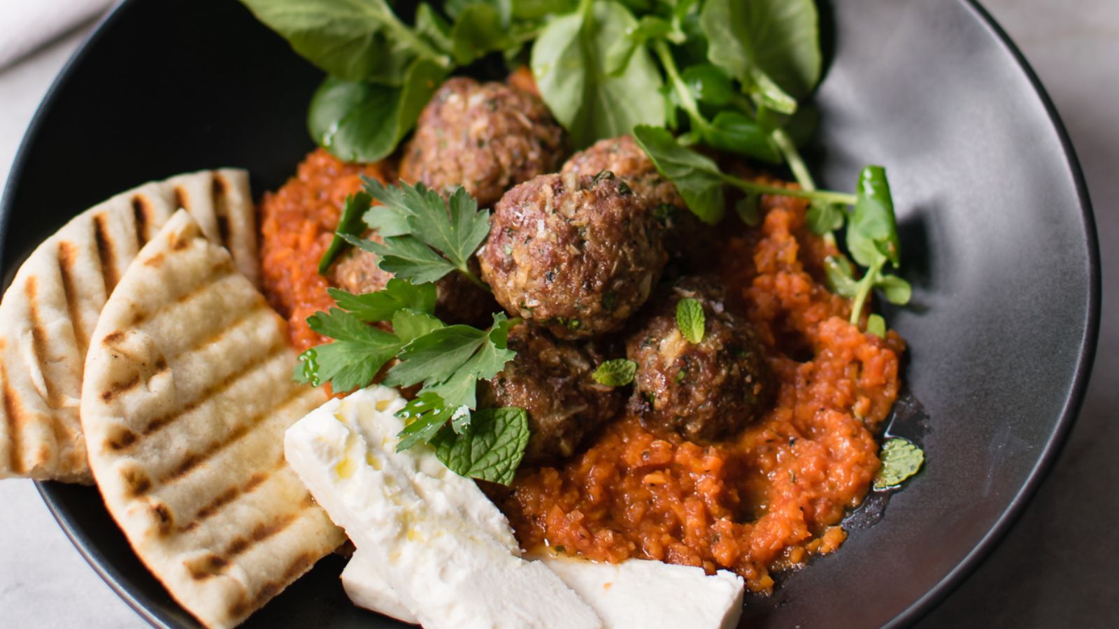 Lamb meatballs with greens and pita bread.
