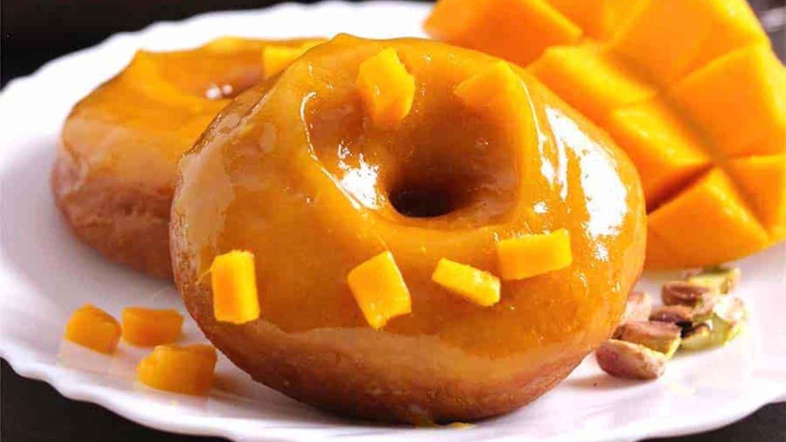 Doughnuts coated in mango sauce and mango bits.