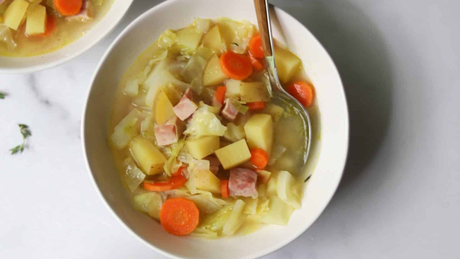 Ham, potatoes and cabbage soup in a bowl.