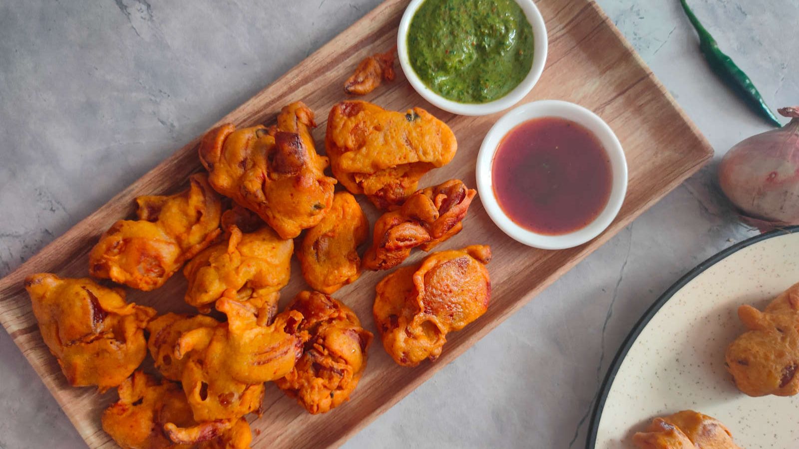 Onion pakora on a wooden board with dips.