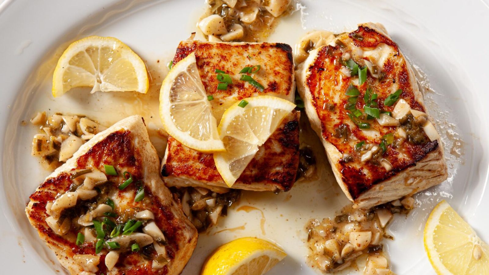 Seared halibut with sliced lemons.