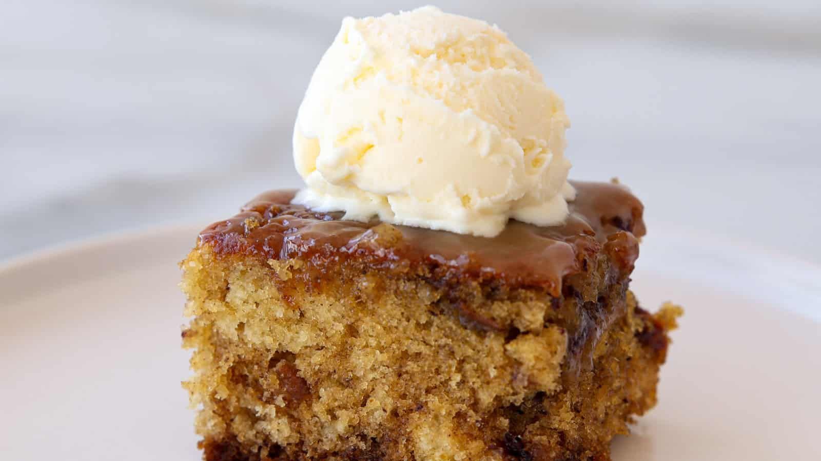 A slice of toffee pudding with a scoop of ice cream on top.