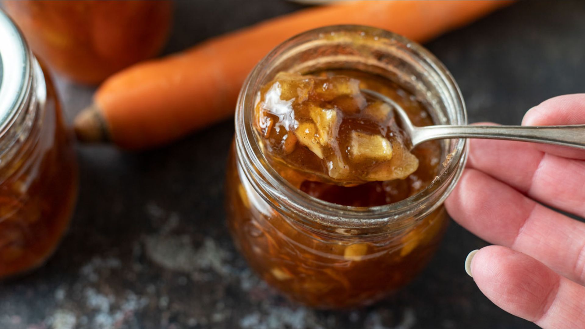 Carrot cake jam in a jar with a spoon scooping some out.