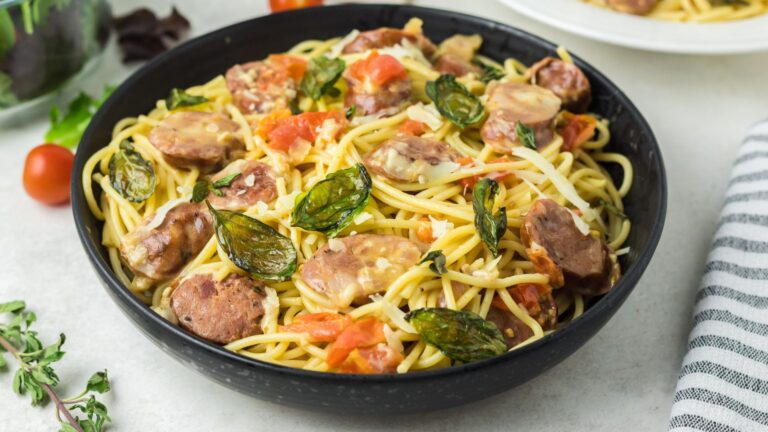 Black bowl filled with colorful pasta and fried basil.