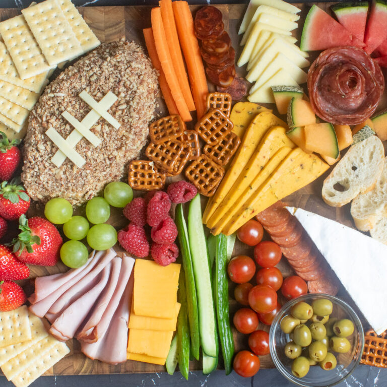 Football charcuterie board with colorful foods.