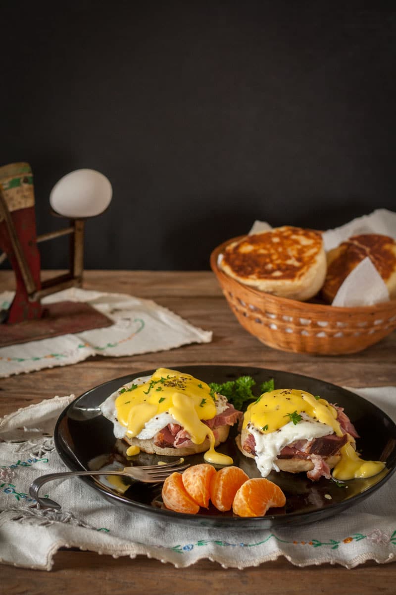 eggs benedict on black plate with antique egg scale in background eggs benedict on black plate with antique egg scale in background