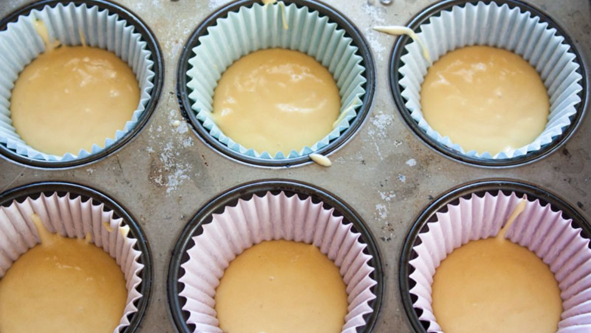 Half filled cupcake liners in a cupcake pan.