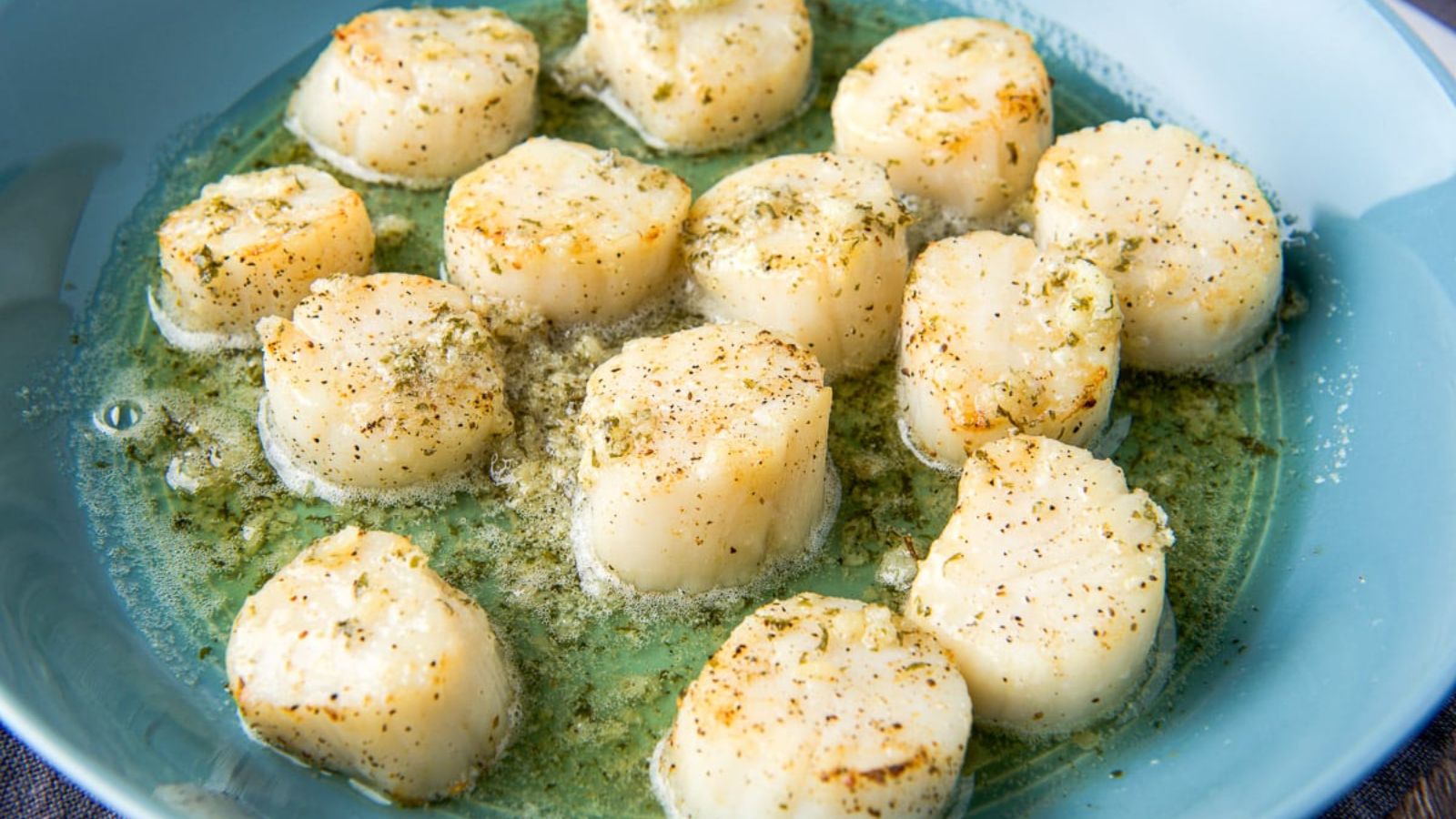 Scallops with butter sauce on a plate.