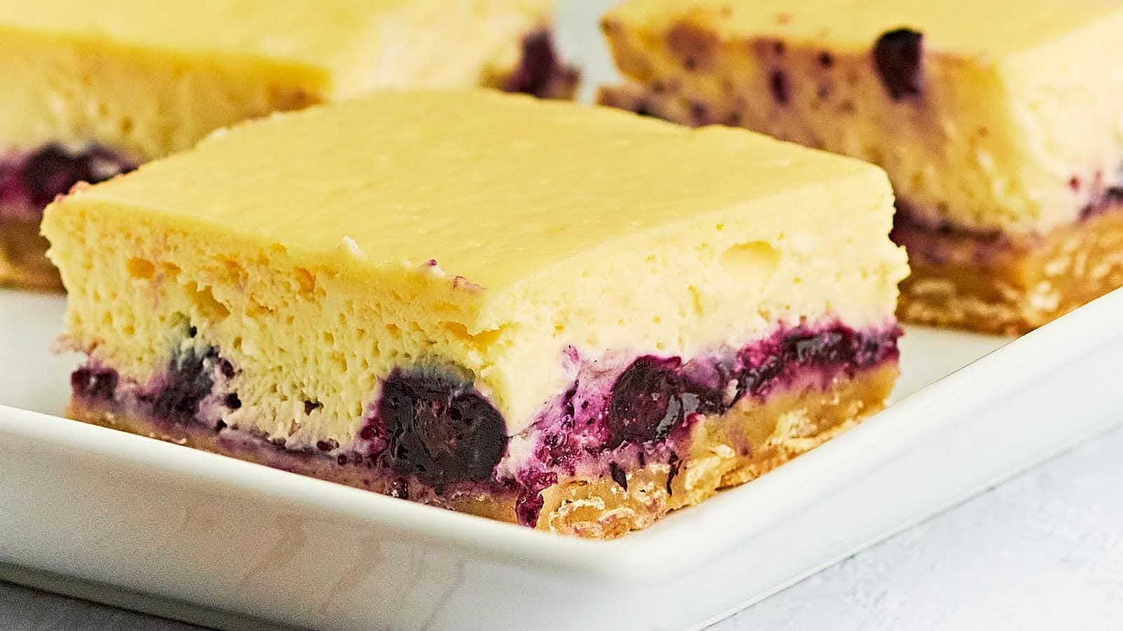 Cheesecake bars with blueberries on a plate.