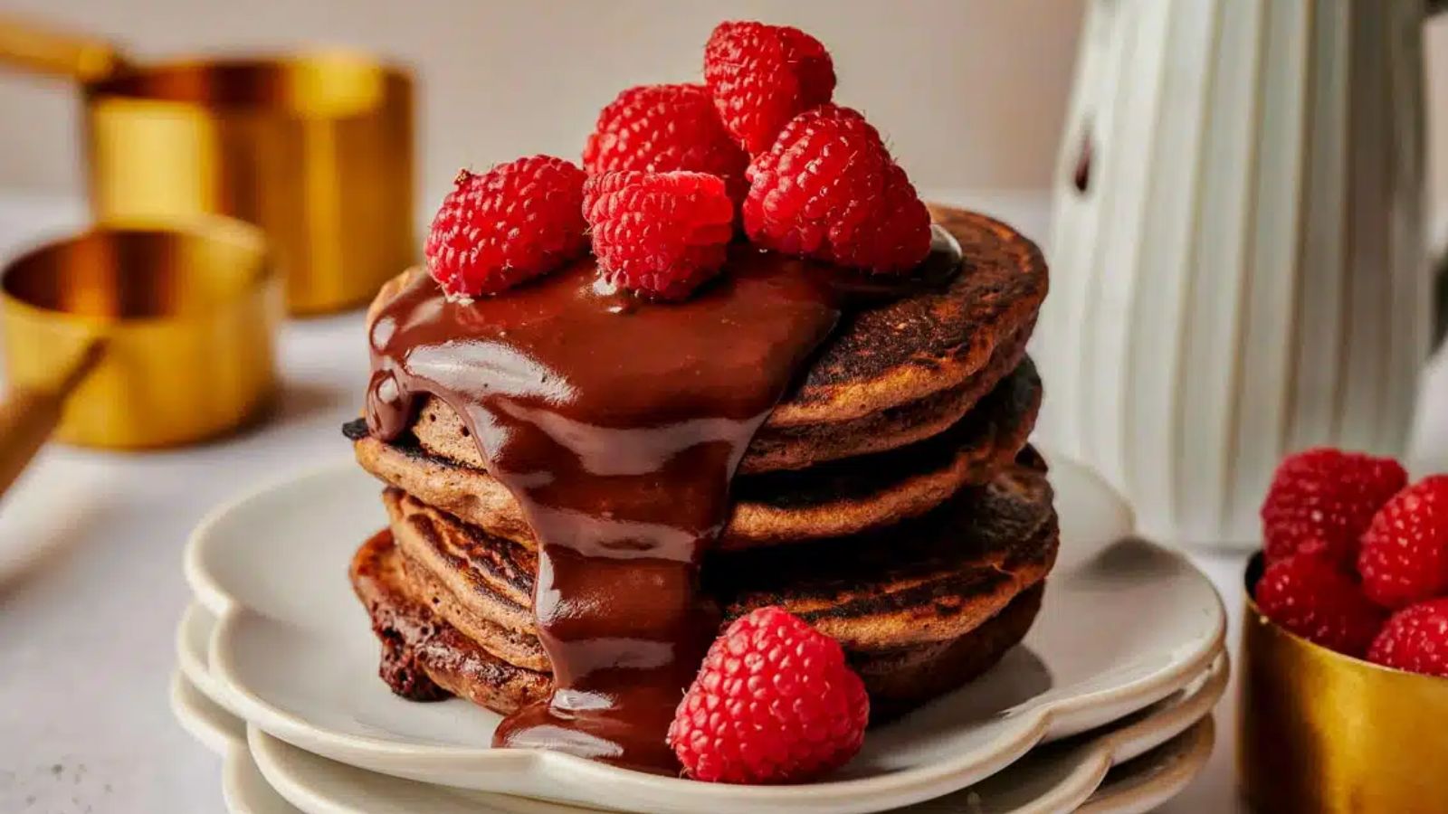 Stack of chocolate pancakes with raspberries on top.