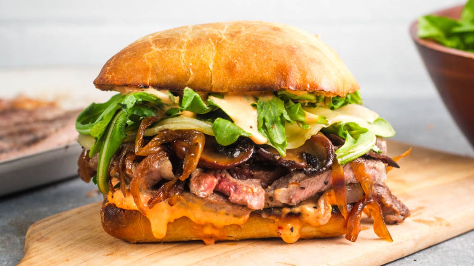 Ribeye steak sandwich on a wooden board.