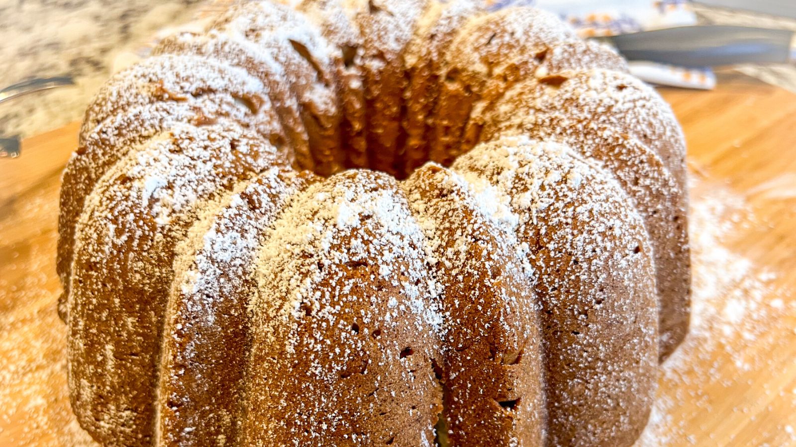 Almond cake with powdered sugar on a wooden board.