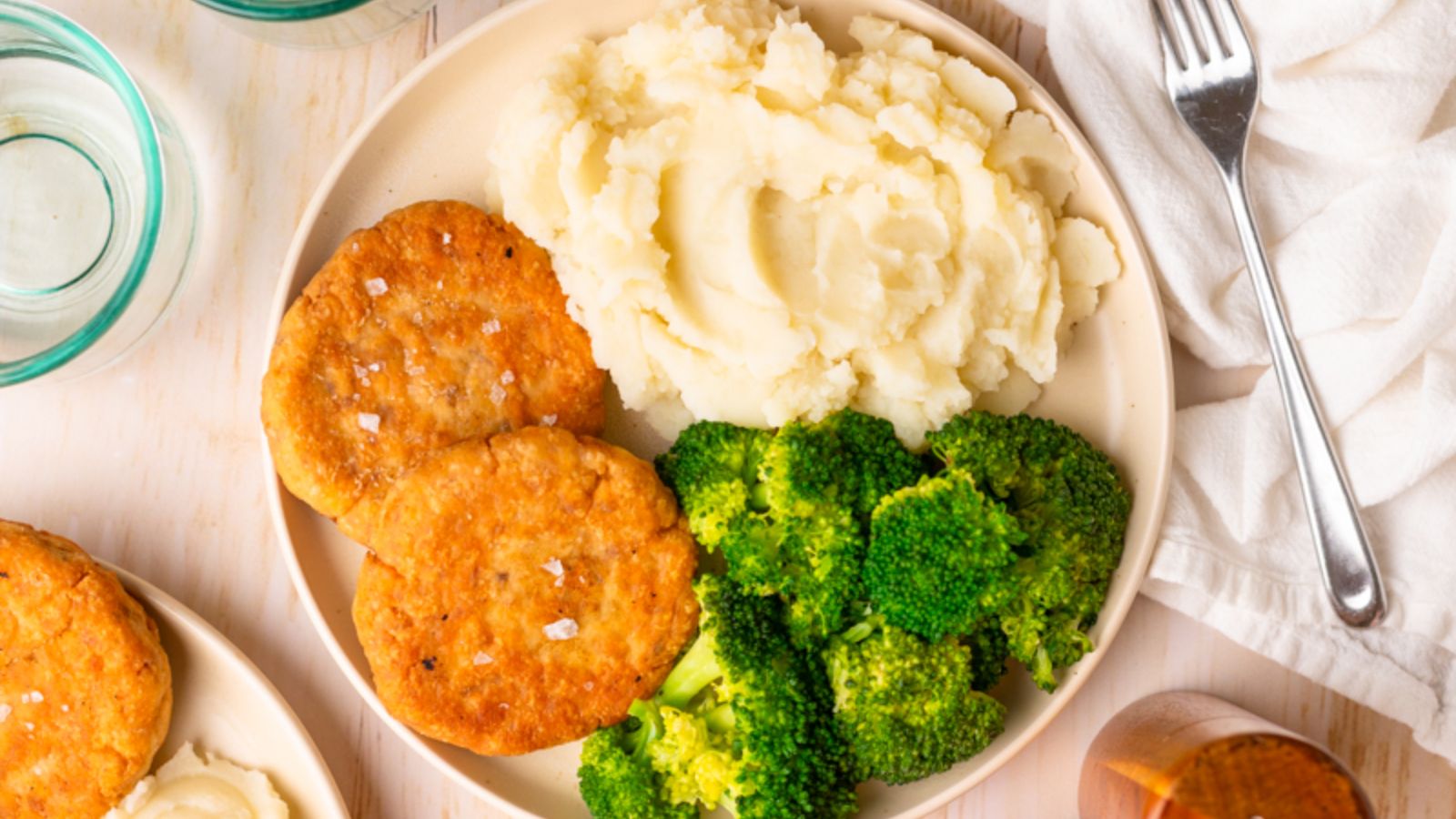 Salmon patties with mashed potatoes and broccoli on a plate.