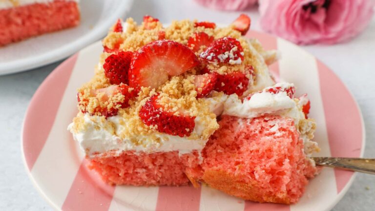 Slice of strawberry cake on a pink and white striped plate.