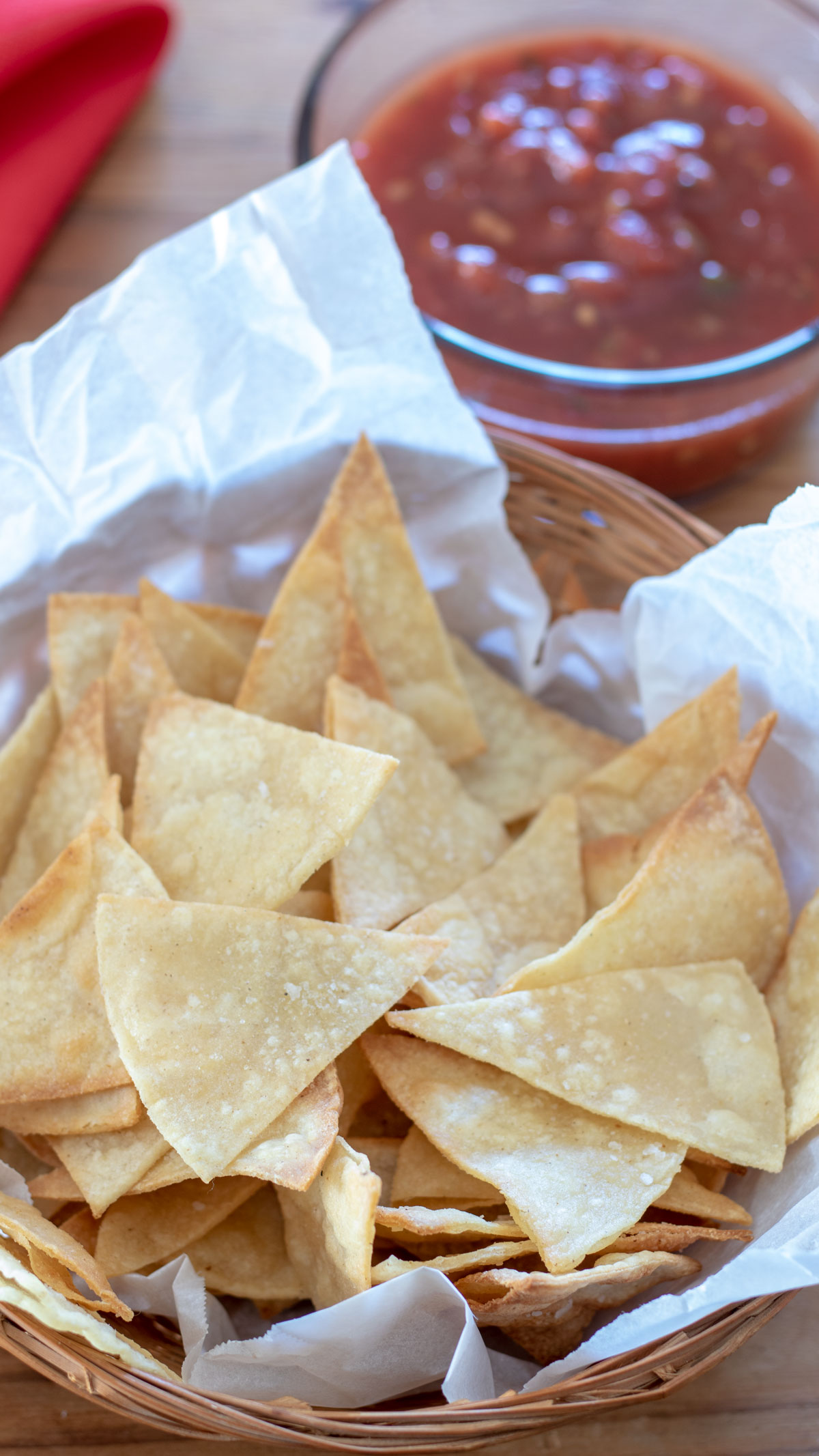 A basket of tortilla chips with salsa if the background.
