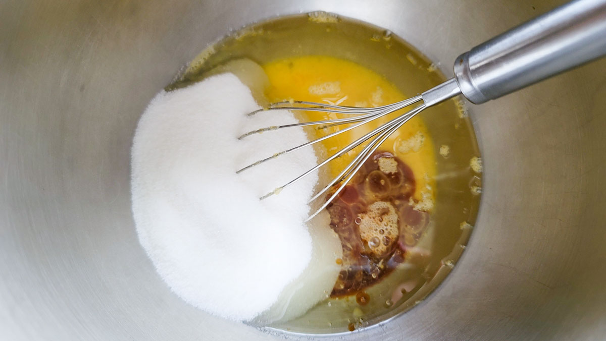 Wet ingredients added to a large bowl with the sugar.