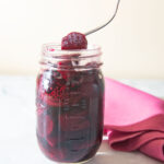 Forking pulling a piece of pickled beet from a jar.