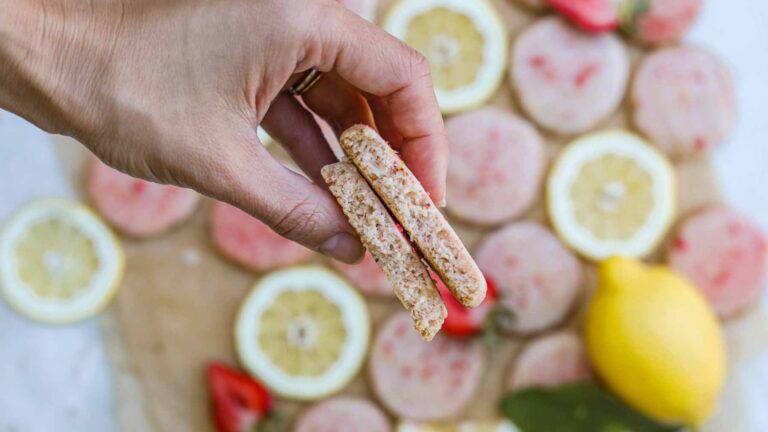 Strawberry lemonade shortbread cut in half with a woman's hand gripping it.