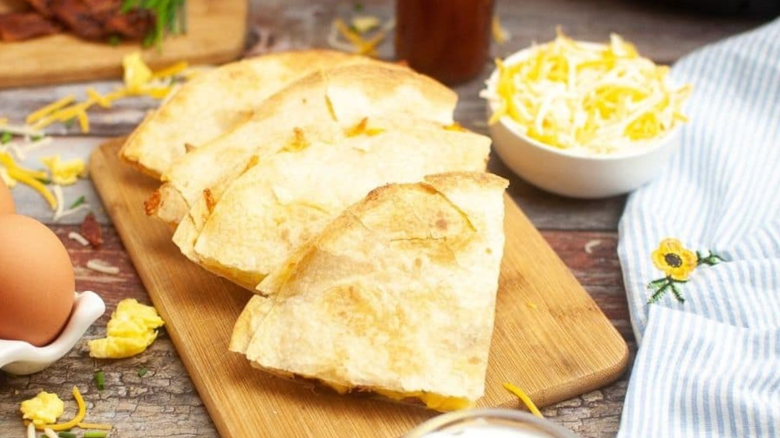 Bacon and egg quesadillas on a wooden board.