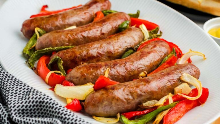 Brats with peppers and onions on a plate.